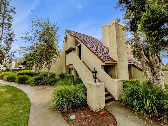 Front view of a residential building with a sloped roof and external stairway.