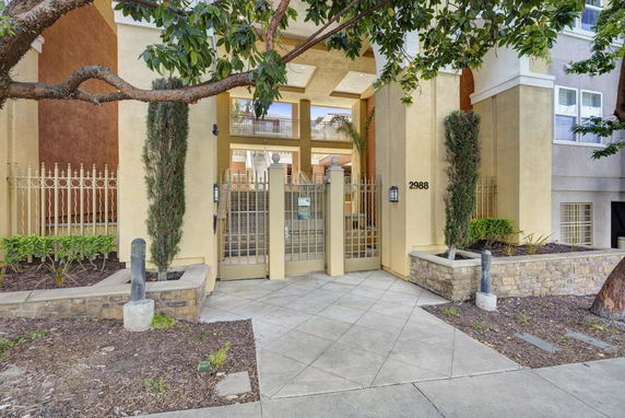 Front view of a building entrance with gated entry and tall pillars.