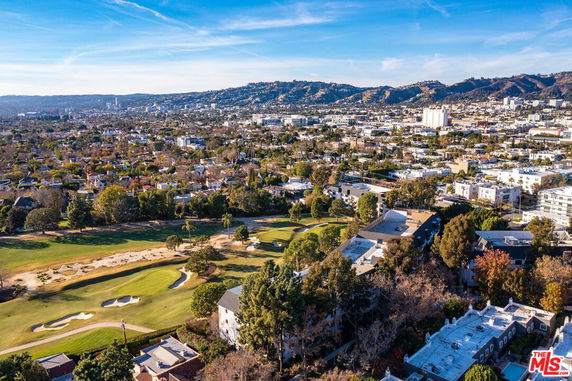 Wide aerial view of a residential area with landscape and hills in the background.