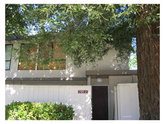 Front view of a two-story house with a tree in front.