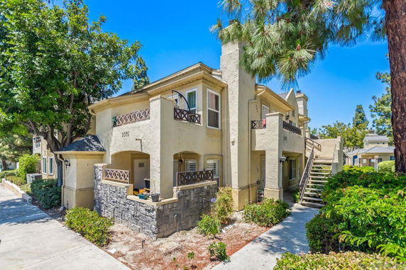 Front view of a two-story beige residential building with outdoor staircases and balconies.