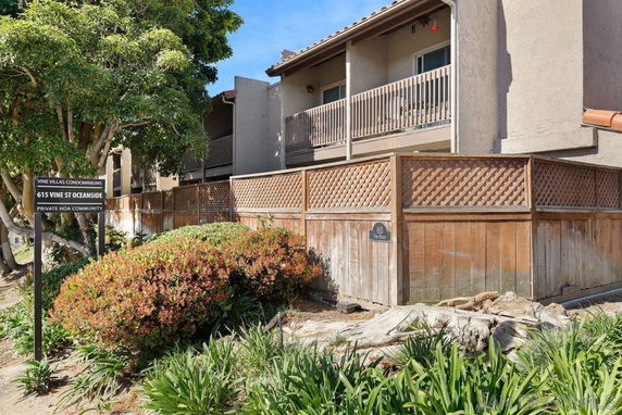 Front view of a multi-story condominium building with wooden fencing and balconies.