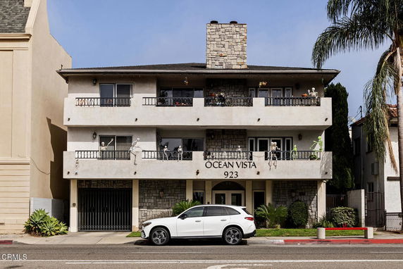 Front view of a three-story apartment building with balconies and stone facade.