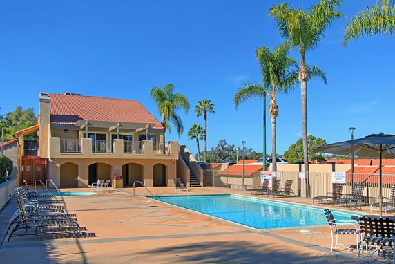 Outdoor swimming pool area with a multi-story building in the background.