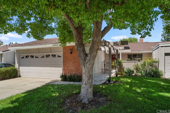 Front view of a single-story house with a garage and brick wall.