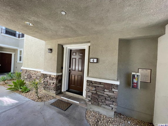 Front view of a modern townhouse entrance with stone accents and a brown door labeled number 4.