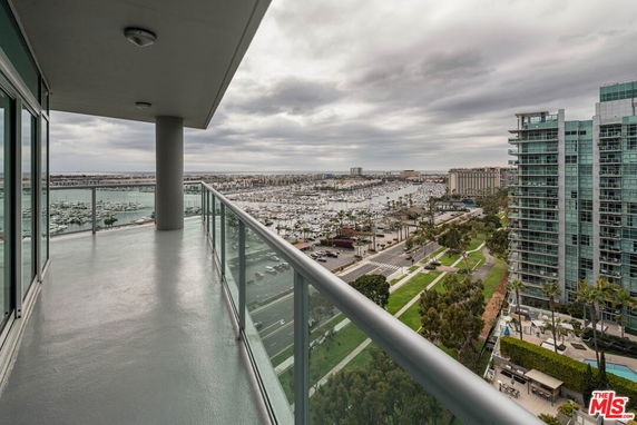 Balcony view overlooking a marina with high-rise buildings and a cloudy sky.