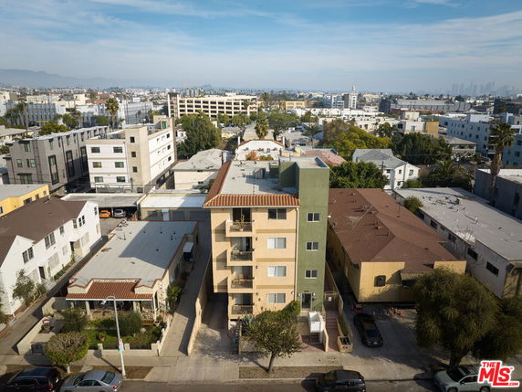 Aerial view of a yellow apartment building surrounded by other residential buildings in an urban area.