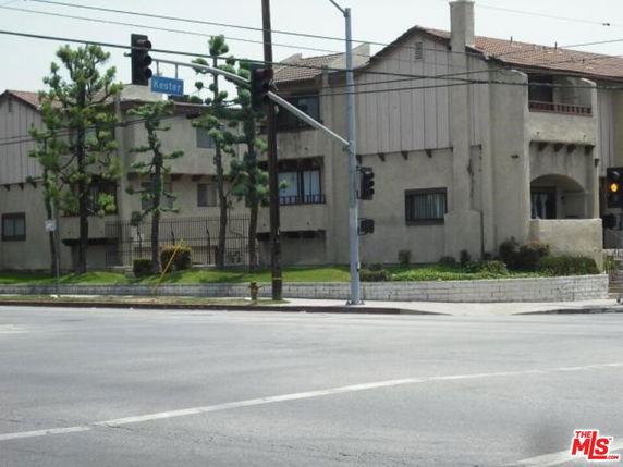 Front view of a multi-story building at an intersection with a sign and streetlights.