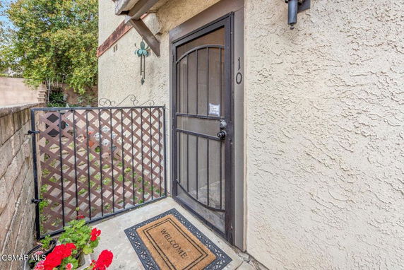 Front view of a house entrance with a metal gate and welcome mat.