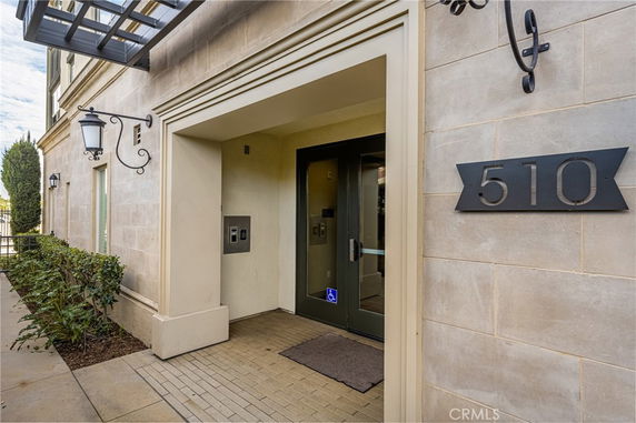 Front view of a building entrance with decorative wall lanterns and a number sign.