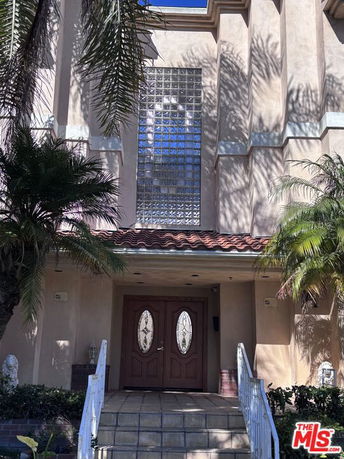 Front view of a house with decorative front doors and glass block windows.