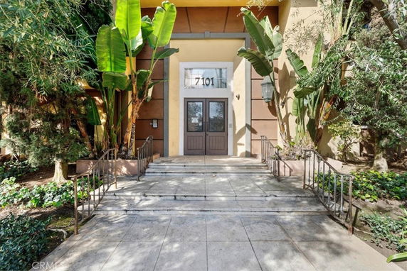 Front view of a building entrance with double doors and surrounding greenery.