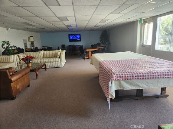 Interior of a clubhouse with couches, tables, and a covered pool or game table.