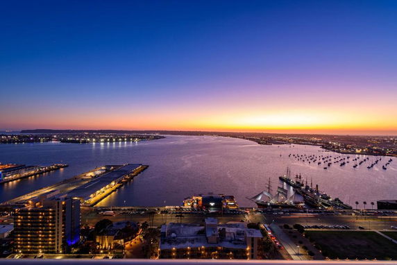 Panoramic view of a bay with city lights at sunset.