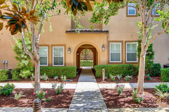 Front view of a house with an arched entrance and windows on either side, surrounded by landscaping.