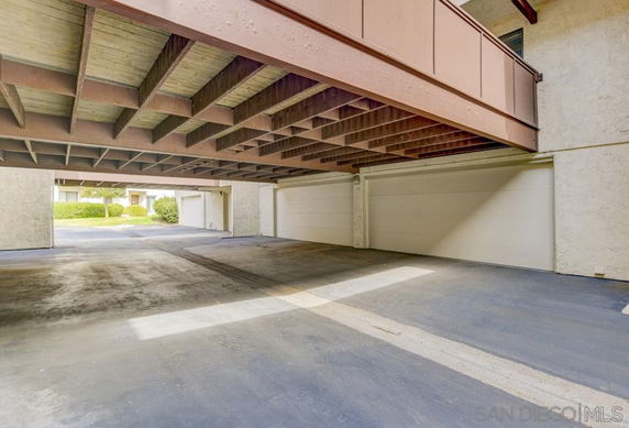Covered parking area beneath a building with multiple garage doors.