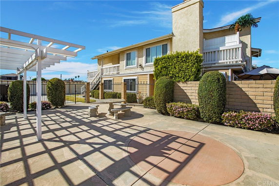 Front view of a two-story building with balconies, fenced area, and adjacent outdoor seating.
