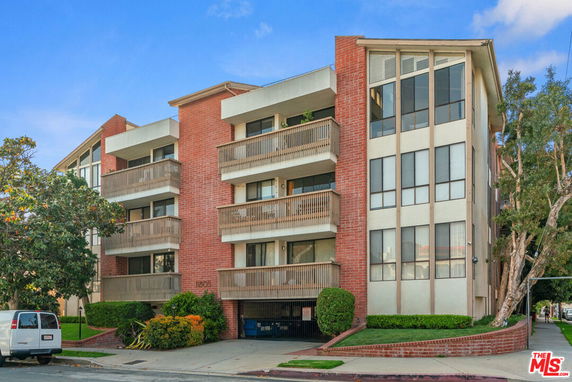 Front view of a multi-story apartment building with brick and glass exterior.