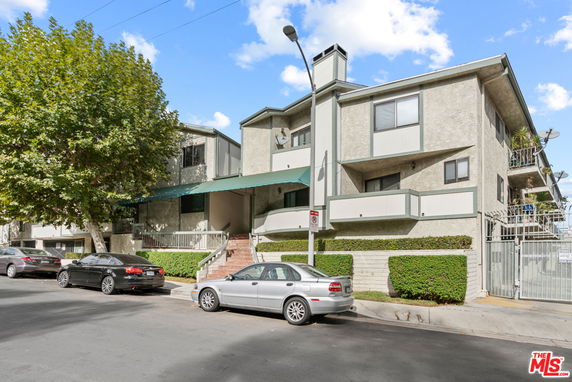 Front view of a multi-story residential building with a gated entrance and balconies.