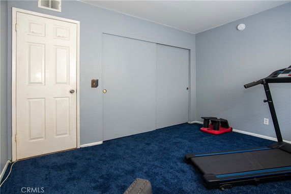 Room with exercise equipment including a treadmill and weights.