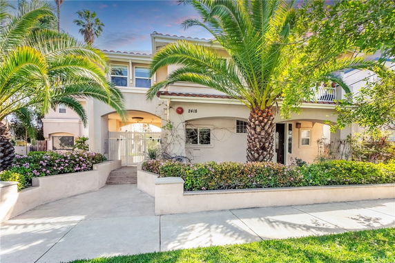 Front view of a two-story house with palm trees and a landscaped entrance.