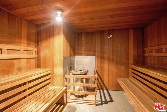Interior view of a wooden sauna room with benches and a heater.
