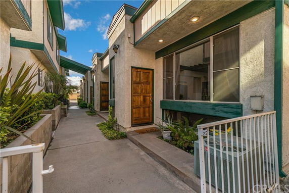 Front view of a series of connected townhouses with wooden doors and green trim.