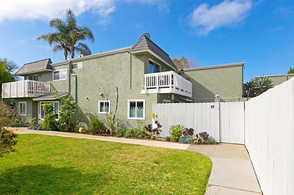 Front view of a two-story house with balconies and a white fence.