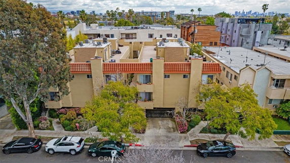 Aerial view of a multi-story residential building with adjacent structures and parked vehicles.