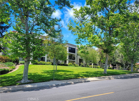 Front view of a multi-story building with balconies and a well-maintained lawn.