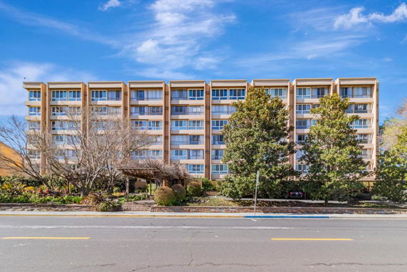 Front view of a multi-story residential building with large windows.