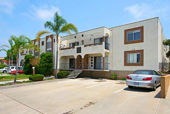 Front view of a two-story apartment building with a parking area in front.