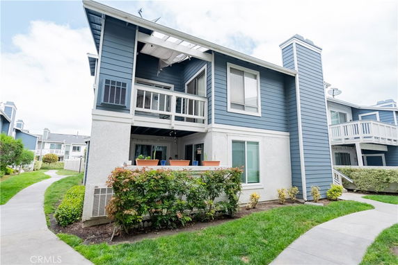 Front view of a two-story residential building with blue siding and balconies.