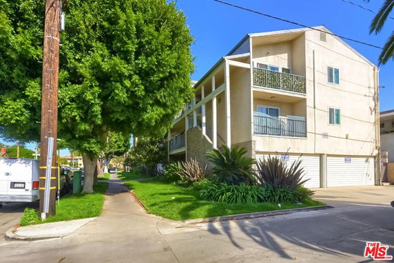 Front view of a multi-story residential building with balconies and garage doors.
