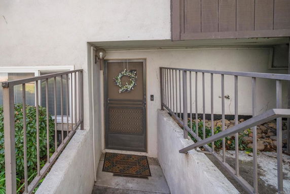 Front view of a building entrance with a wreath on the door and a welcome mat.