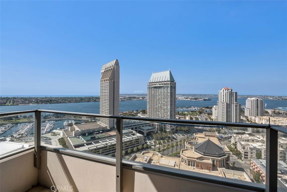 Panoramic view from a high-rise building showcasing a cityscape with tall buildings and water bodies in the distance.