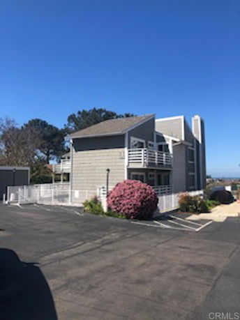 Front view of a two-story house with balconies and a pitched roof.