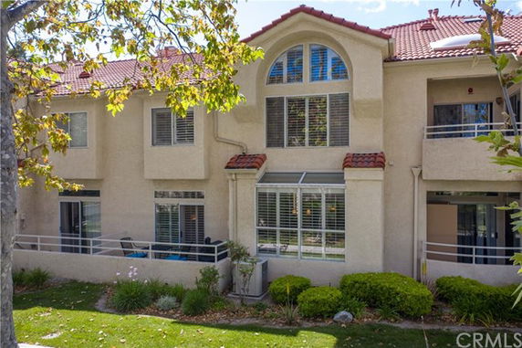 Front view of a multi-story house with a red-tiled roof and large windows.