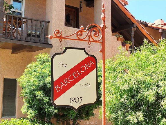 Front view of a building with a sign that reads 'The Barcelona' and a balcony.