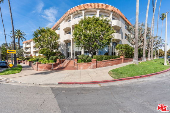 Front view of a multi-story building with brick and stucco exterior and balconies.