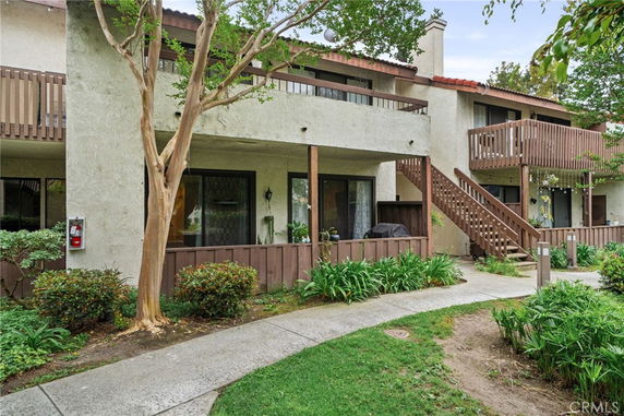 Front view of a two-story building with wooden balconies and a staircase.