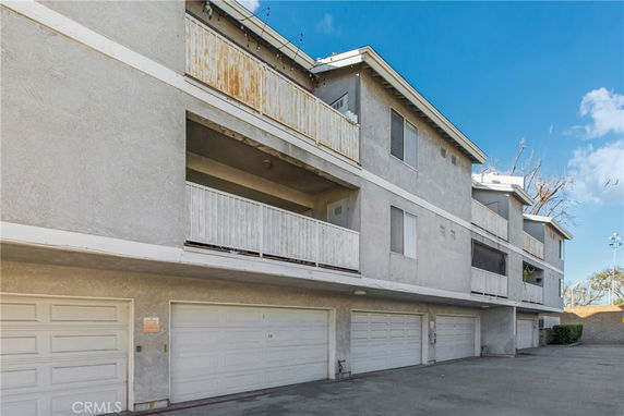 Front view of a multi-story building with garages and balconies.