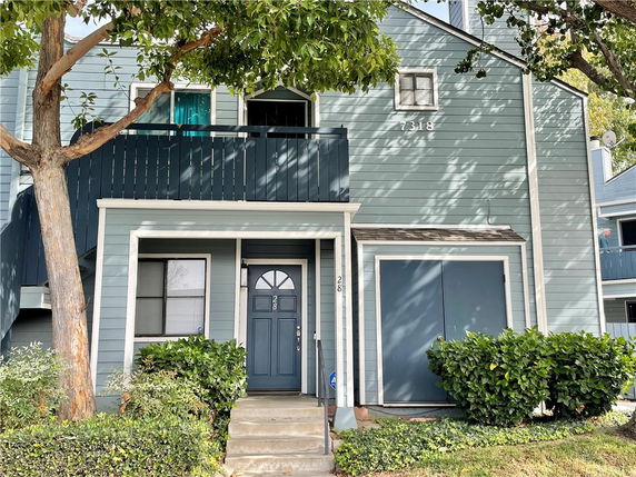 Front view of a two-story house with a balcony and teal exterior.