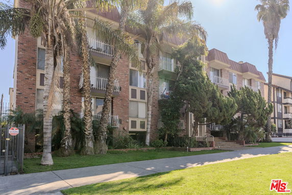 Front view of a multi-story residential building with balconies and brick exterior.