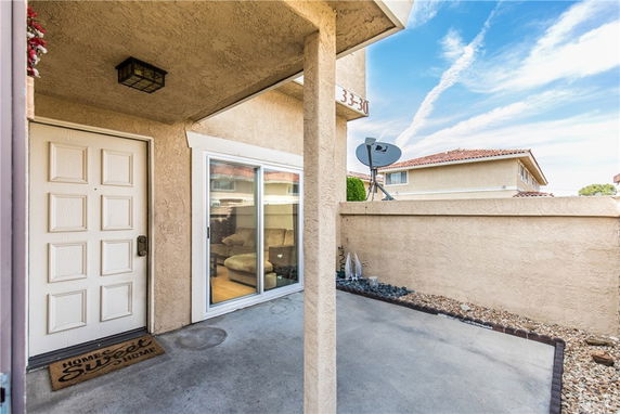 Front view of a house entrance with a white door and sliding glass doors leading to an interior space.