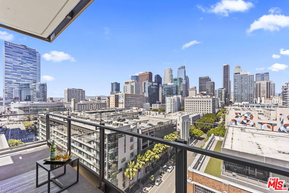Panoramic view of city skyline from a balcony with glass railing.