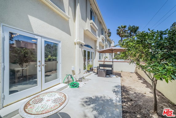 View of a multi-story house exterior with patio, glass doors, and an umbrella.
