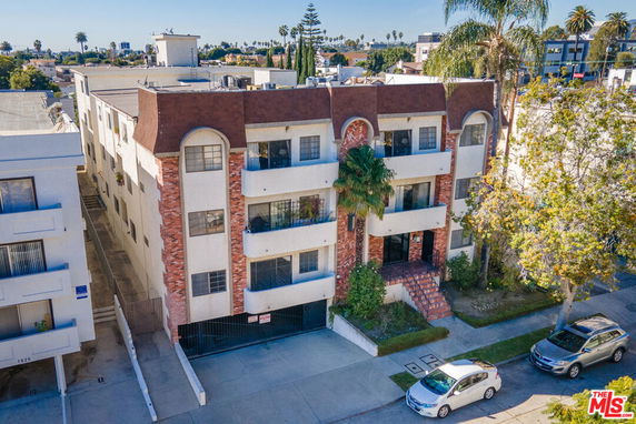 Front view of a multi-story apartment building with balconies and brick accents.