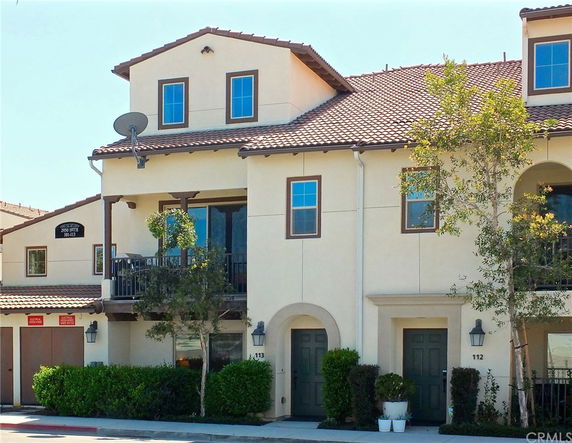 Front view of a multi-story house with a balcony and tiled roof.